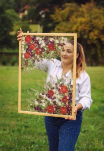 Autorka drží hotový obraz z lisovaných svatebních květin na zeleném pozadí